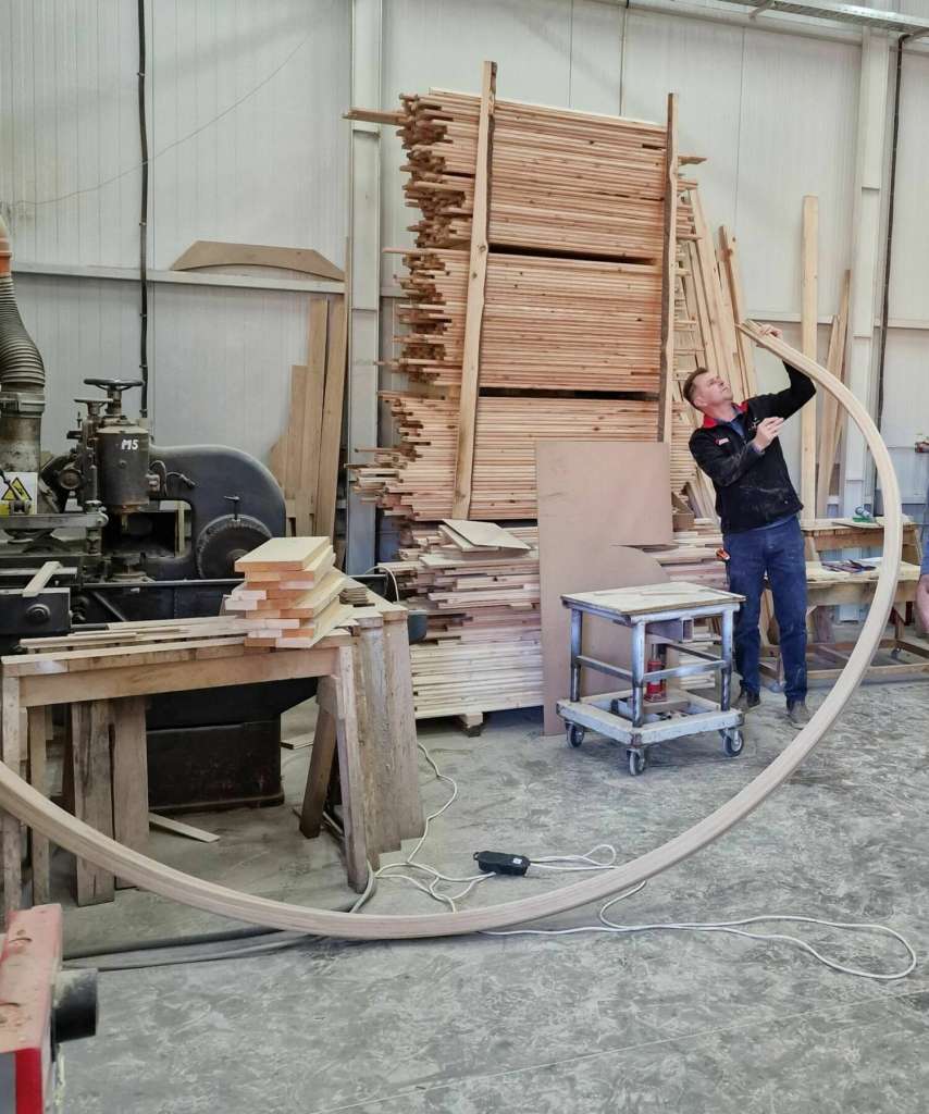 Skilled craftsmen meticulously assembling components of a bespoke staircase in workshop.