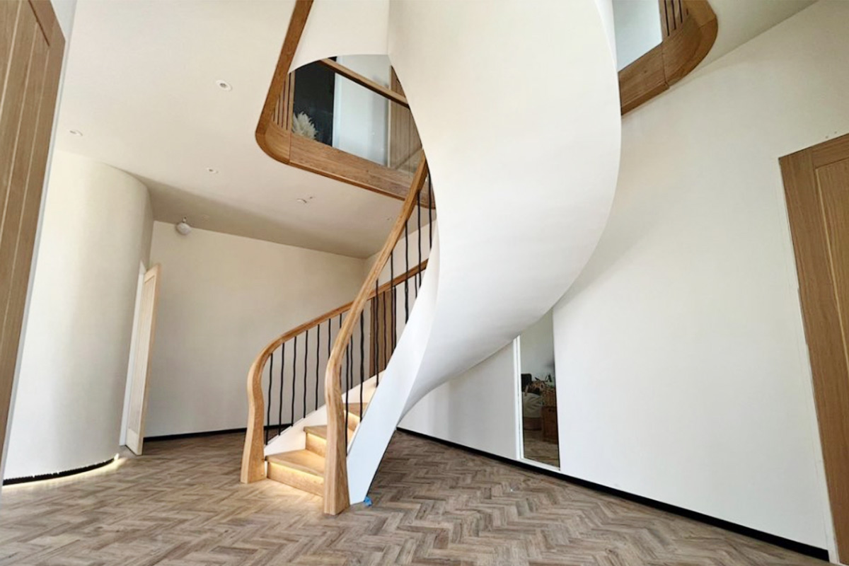 Handmade helical staircase by Apex Staircases, UK. Bespoke walnut and glass curved design, manufactured in Britain.